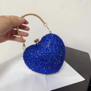 Close-up of heart-shaped evening bag with royal blue rhinestones and gold ring handle