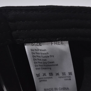 Detail view of cotton baseball cap washing label showing 100% cotton fabric and care instructions