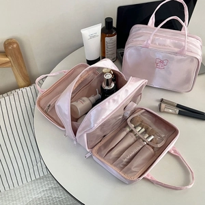 Dettaglio interno del beauty case in raso rosa con scomparti per pennelli e trucco