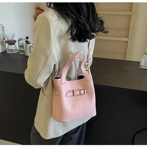 Detail of pink lychee grain leather bucket bag with metal buckle and crossbody strap