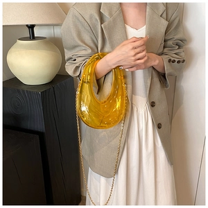 Detailed view of translucent yellow crescent acrylic handbag with elegant gold chain strap