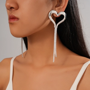 Close-up of model wearing silver heart stud earrings with sparkling tassel drop pendants
