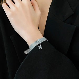Close-up of silver mesh bracelet with star pendant on model wearing black blazer
