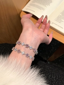Detail of silver flower bracelets with pink and clear zircons on female wrist