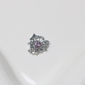 Macro detail of silver spiderweb pendant with pink heart gemstone and white crystals