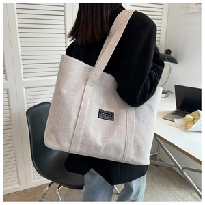 Large beige tote bag side view showing capacity and thick shoulder strap on model