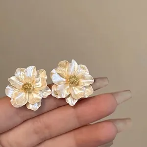 Detail of pearlescent flower earrings with golden centers and champagne petals