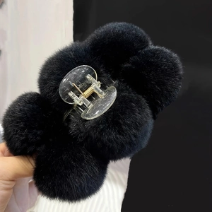 Plush faux fur hair claw clip featuring soft black fur balls and gold metal spring