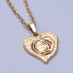 Macro detail of a vintage golden heart pendant with a unique hammered texture on a chain