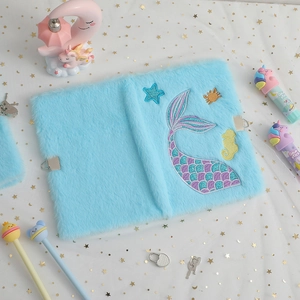 Detail of light blue plush notebook with mermaid tail embroidery and metal lock