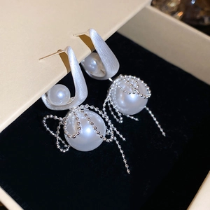 Macro detail of silver tassel earrings featuring white pearls and brushed metal finish
