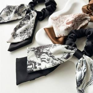 Close-up of elegant satin scrunchies with long streamers in classic black and white toile patterns