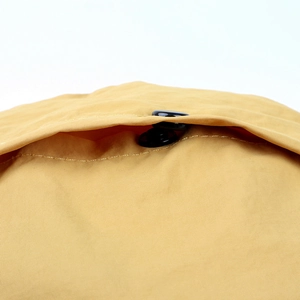 Macro detail of ginger yellow quick-dry fabric and black button on women's sun hat