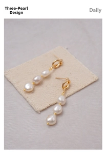 Macro shot of French vintage pearl earrings featuring gold knot details and three white pearls