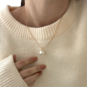Elegant white pearl pendant necklace with gold chain shown on model in natural lighting