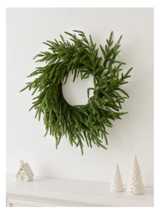 Realistic Norfolk pine Christmas wreath hanging above a white festive fireplace mantle