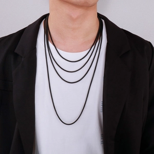 Detail of layered black titanium steel chains on a model with street style outfit