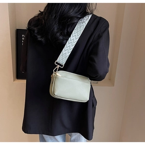 Detail of sage green PU leather crossbody bag with wide geometric woven shoulder strap