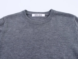 Détail du col rond côtelé et de la texture en maille fine de ce pull gris foncé