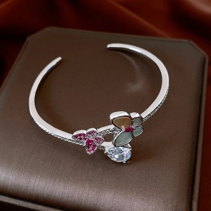 Detail view of silver zircon butterfly bangle with mother-of-pearl flowers on brown silk