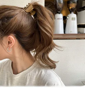 Dettaglio di una pinza per capelli kaki opaca e orecchini a cerchio in argento