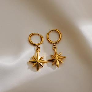 Close-up of gold plated s925 silver star earrings on elegant white silk fabric