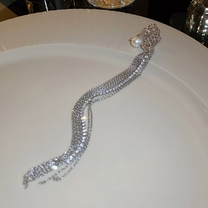 Detail of silver liquid metal ear clip with a white pearl and long chain tassels