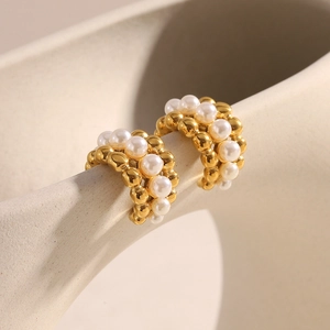 Detail view of 18K gold plated C-shaped earrings with pearls on ceramic display