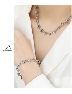 Close-up of a silver stainless steel knotted chain necklace and bracelet set for women