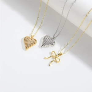 Minimalist gold and silver heart necklaces with pave zircon pendants on a white background