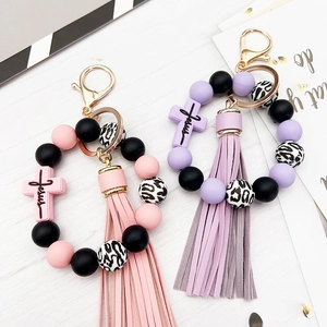 Detail of cross charm keychain with silicone beads, tassels and Jesus engraving