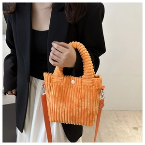 Close-up of bright orange corduroy bucket bag featuring pleated handles and shoulder strap