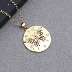 Detail of gold necklace with round pendant featuring a butterfly set with colorful stones