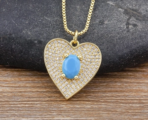 Macro detail of gold heart pendant with white zircons and center turquoise stone