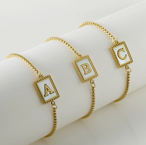 Detailed view of adjustable gold-tone letter A, B, C shell bracelets on a white pedestal