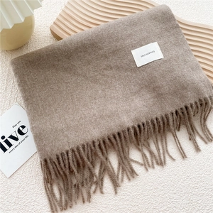 Detail of soft solid color winter scarf with thick fringe and minimalist woven label