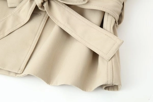 Macro detail of khaki trench coat belt knot showing fine twill fabric and neat stitching
