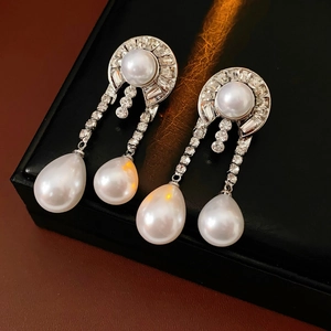 Macro di orecchini di perle a goccia in argento con diamanti su espositore in pelle
