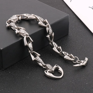 Detail of silver fish-scale chain bracelet with heart clasp and wing pendant accessory