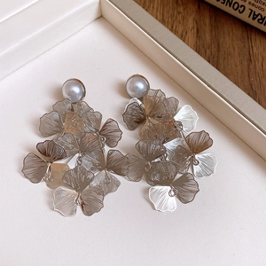 Détails de boucles d'oreilles à fleurs avec perles blanches et pétales en métal argenté