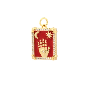 Detail of 18k gold plated Hamsa hand pendant with red enamel and inlaid zircons