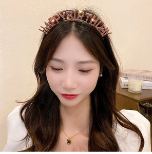 Close-up of golden Happy Birthday headband with pink rhinestones on a female model