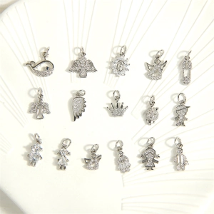 Silver jewelry charms featuring angel and star shapes arranged on a white shell plate