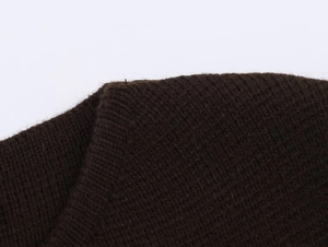 Gros plan sur la maille épaisse et la couture d'épaule de ce gilet en tricot marron