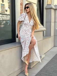 Détail d'une robe longue fleurie à col en V avec manches bouffantes et fente