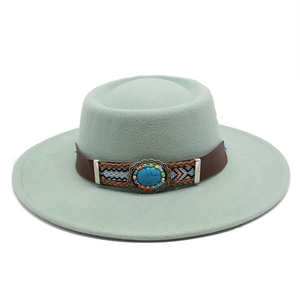 Close-up of mint green wide-brim fedora hat with ethnic woven band and turquoise brooch