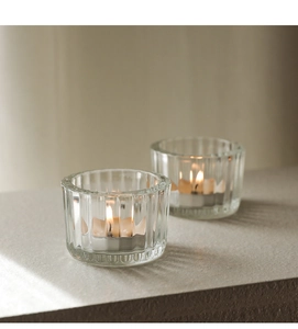 Detail view of vertical ribbed crystal glass tea light holders with a lit candle inside