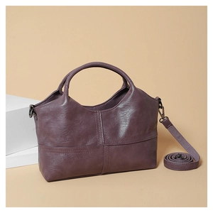 Detail view of deep purple soft leather handbag with stitching and adjustable shoulder strap