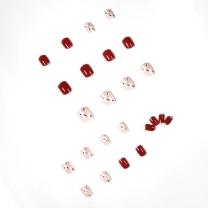 Faux ongles courts et ronds bordeaux et roses avec motifs floraux sur fond blanc