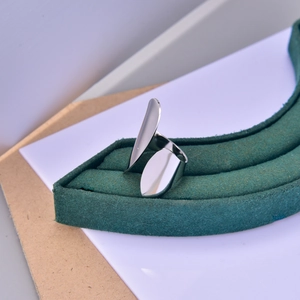 Close-up of minimalist silver open ring with unique asymmetrical double-wing metal design